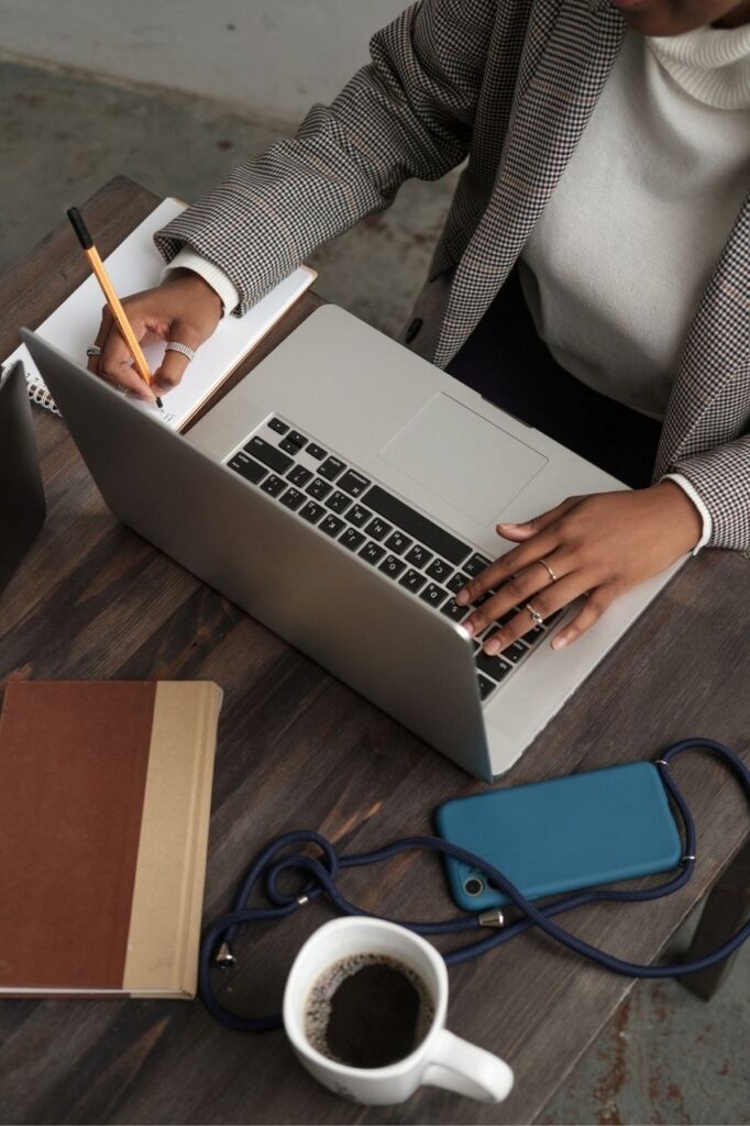 Businesswoman Writing Notes While Using Laptop 1